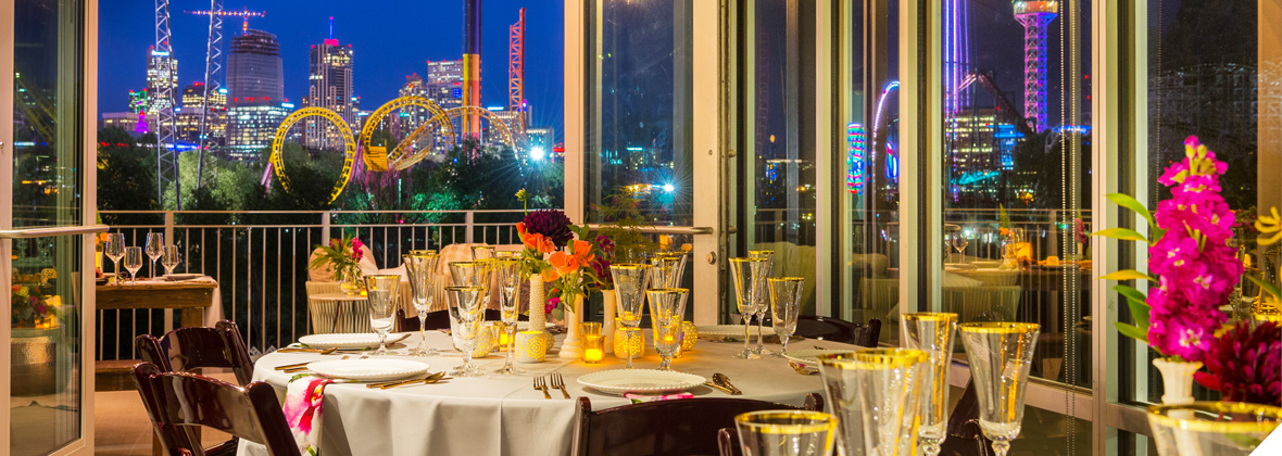 A glamorous event space with beautiful table settings and decorations overlooking the cityscape.