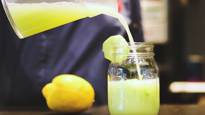 glass of cucumber lemonade being poured from a pitcher